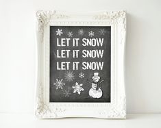 a chalkboard with snow written on it in front of a white frame and the words let it snow, let it snow