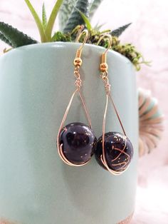 Black and gold colored swirled beads sit in a lovely drop setting. Wire Wrapped Teardrop Earrings For Party, Teardrop Gold Beads Earrings For Party, Black Beaded Teardrop Earrings For Gift, Teardrop Black Beaded Earrings As Gift, Teardrop Black Beaded Earrings For Gift, Teardrop Earrings With Black Beads For Gifts, Gold Teardrop Earrings With Round Beads For Gifts, Gold Beaded Earrings With Black Beads For Party, Handmade Black Teardrop Earrings For Party