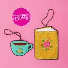 a tea cup and book on a pink background with a tag attached to the back