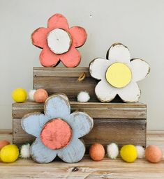 three wooden flowers sitting on top of each other with pom poms around them