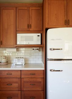 a white refrigerator freezer sitting in a kitchen next to wooden cabinets and counter tops