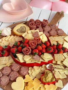 an assortment of cheeses, crackers and strawberries on a platter