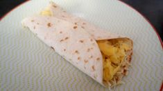 a burrito on a plate with eggs and cheese