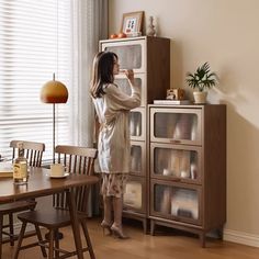 a woman standing in front of a cabinet