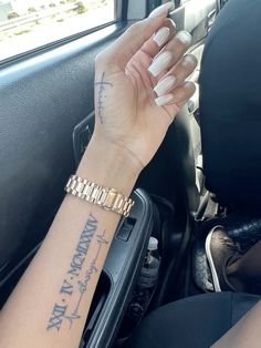 a woman's arm and wrist with writing on it in a car, while she is holding the steering wheel