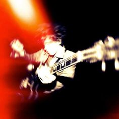 a blurry photo of a man playing an electric guitar with his hands and neck