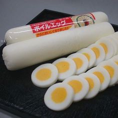 eggs are arranged in rows on a black tray with an orange stick and some yogurt