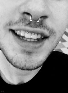 a man with piercings on his nose smiling