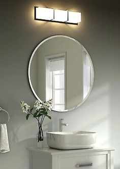 a white sink sitting under a round mirror