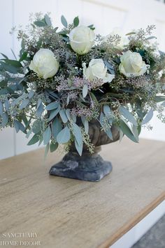 a vase filled with white flowers on top of a wooden table