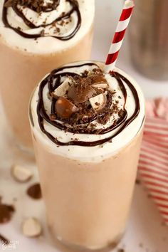 two glasses filled with chocolate milkshakes and topped with whipped cream, candy canes