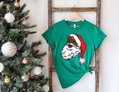 Black Santa Claus Shirt, Black Santa Claus Tee, African American Christmas Tee, African American Santa Shirt, Christmas Tee, Xmas Gift Shirt 📢Please Check All Photos For Details.   📢Choose Your T-Shirt Size From The Drop-Down Lists Next To The item Picture   📢Choose Of Your T-Shirt Color From The 2nd Picture   📢Use "Add message to Seller" link On The Checkout Page To Send me the Following important Details For Your Order's Customization.   📢Shipping Time Varies by location (we are located i Christmas Vacation Shirt, Funny Santa Shirts, Retro Christmas Shirt, Christmas Vacation Shirts, Santa Shirt, Sugar Land, Funny Santa, Black Santa, Santa Shirts