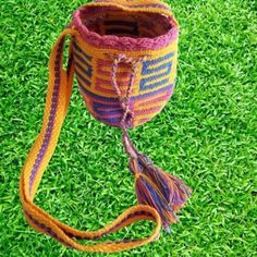 a crocheted bag with a tassel hanging from it's side on the grass