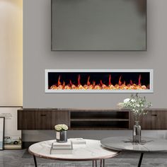 a living room with two tables and a television mounted on the wall above an electric fireplace