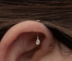 a woman's ear with a single diamond in it