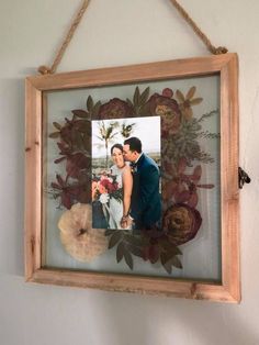 a wooden frame hanging on the wall with an image of a bride and groom in it