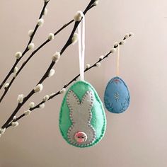 two felt easter eggs hanging from a tree branch