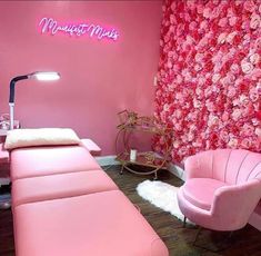 a room with pink furniture and flowers on the wall, along with a neon sign