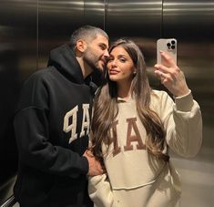 a man and woman taking a selfie in an elevator