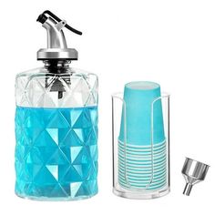 a blue glass bottle next to a toothbrush holder and an empty cup on a white background