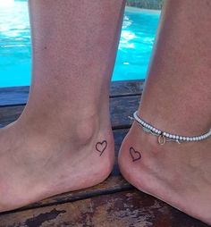 two feet with hearts tattooed on them next to a pool