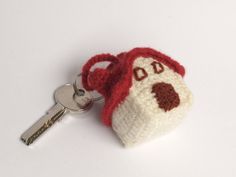 a crocheted keychain with a red and white dog face on it