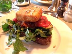 a sandwich with lettuce and tomato on it sitting on a plate at a restaurant