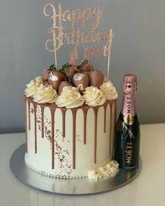 a birthday cake with chocolate icing and strawberries on top next to a bottle of champagne