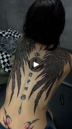 the back of a woman's body with tattoos on her chest and wings painted on it