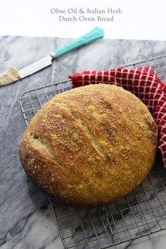 a loaf of bread sitting on top of a cooling rack next to a red and white towel