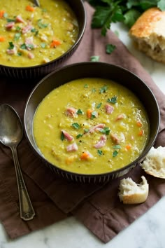 two bowls filled with soup on top of a table next to bread and parsley