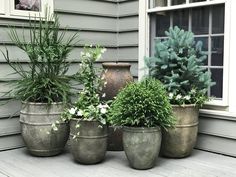 three planters with plants in them sitting on a porch