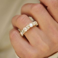 a woman's hand wearing a gold ring with three stones on the middle and one stone in the middle