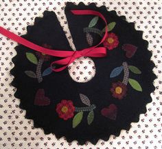 a black ornament with red ribbon and flowers on it