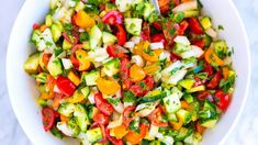 a white bowl filled with cucumber, tomatoes and other vegtables