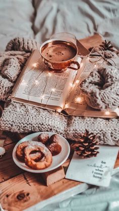 a cup of coffee and some doughnuts on a tray with a book, lights