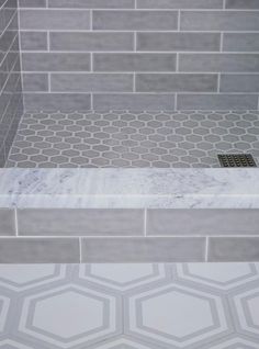 a bathroom with grey tile and white hexagonal tiles