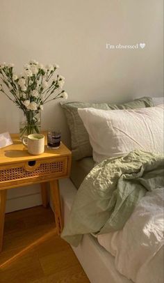 a small table with flowers on it next to a bed