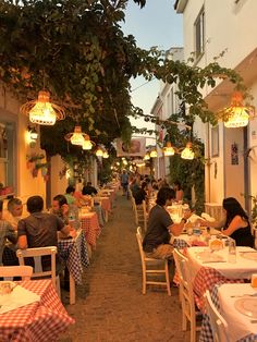 people are sitting at tables in an outdoor dining area with checkered tablecloths