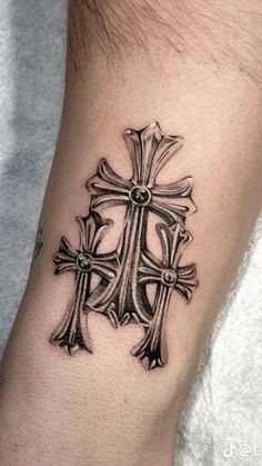 a cross tattoo on the wrist is shown in black and grey ink, with an intricate design