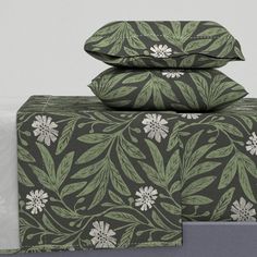 three pillows and two pillow cases on top of each other with floral designs in green