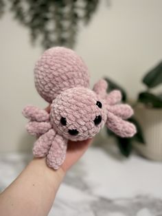 a hand holding a small pink crocheted octopus