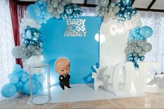 a baby shower is set up with blue and silver balloons, an elephant statue, and a balloon arch