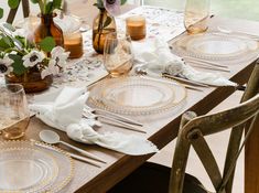 the table is set with white and gold plates, silverware, and flowers in vases