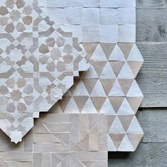 a wall made out of white and grey tiles with geometric designs on it's sides