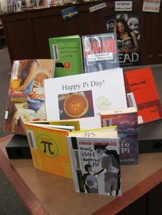 there are many books on the table and one has a sign that says happy pi day