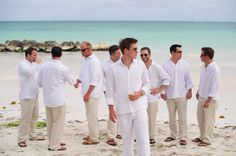 a group of men standing next to each other on top of a white sandy beach