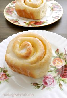 two plates with rolls on them sitting on top of a wooden table next to each other