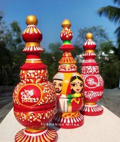 three red and yellow vases sitting on top of a white table next to each other