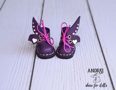 a pair of purple shoes with hearts on them sitting on top of a white wooden floor